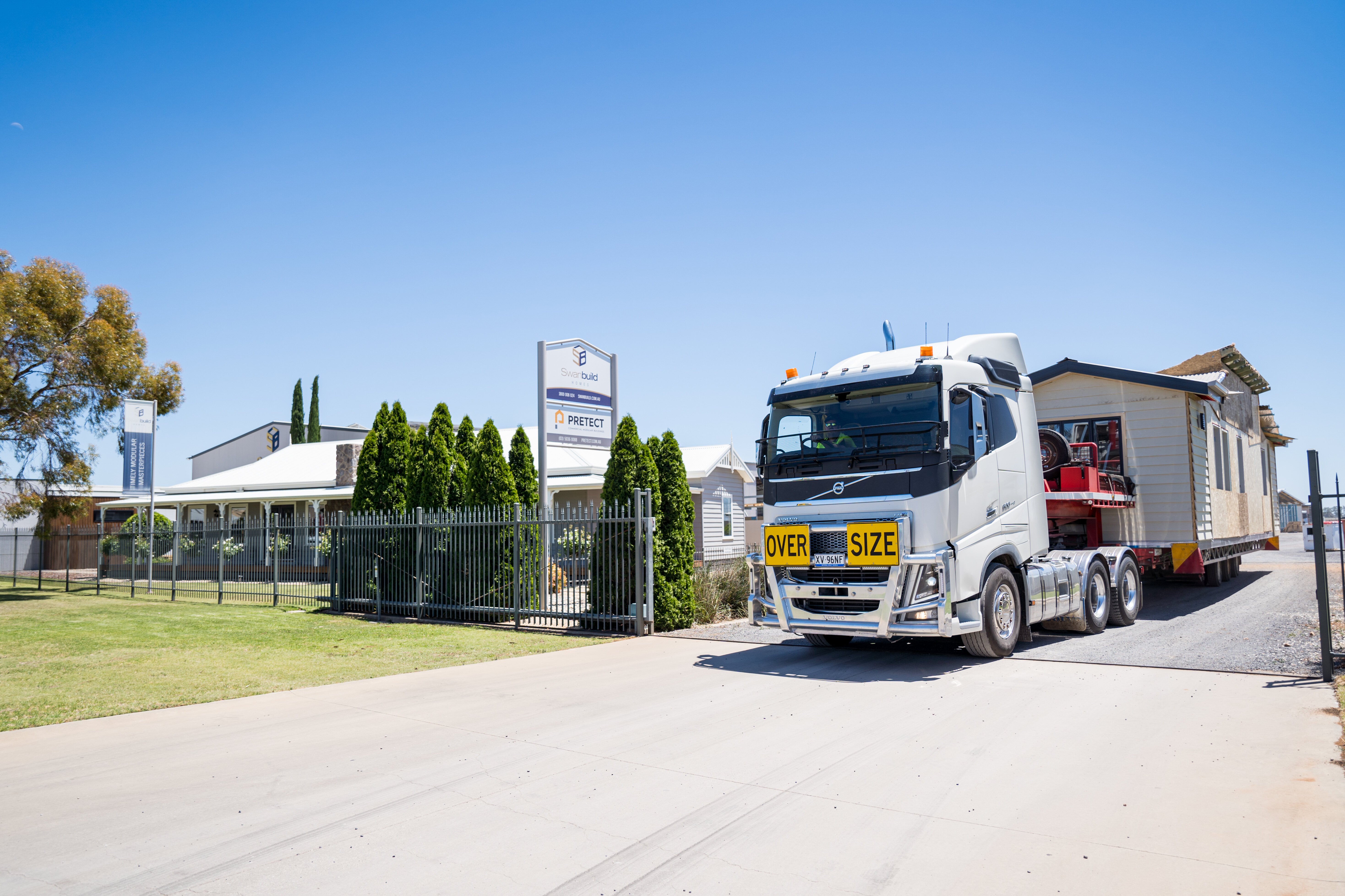 Truck with home on tray leaving factory